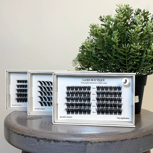 Eyelash extensions in clear cases on a wooden stool with a plant in the background